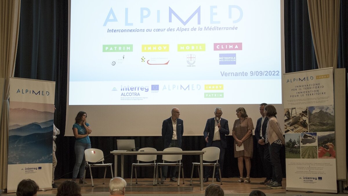 Nella fotografia il presidente del Parco Piermario Giordano sul palco del teatro di Vernante saluta i partner di progetto riuniti in assemblea. Fine descrizione foto.